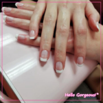 Hands showing a new set of french-tip square nails, on a pink backdrop.