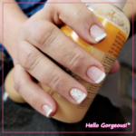 Hands showing sparkly french-tip nails with a snowflake as a detail on the ring finger nail.