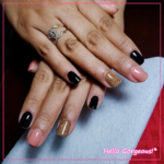 Hands showing a fresh set of black, pink, and shimmery golden nails.